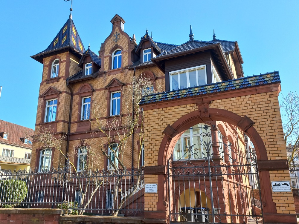 Historisches Backsteingebäude des Instituts für pfälzische Geschichte und Volkskunde mit charakteristischem Turm und Torbogen