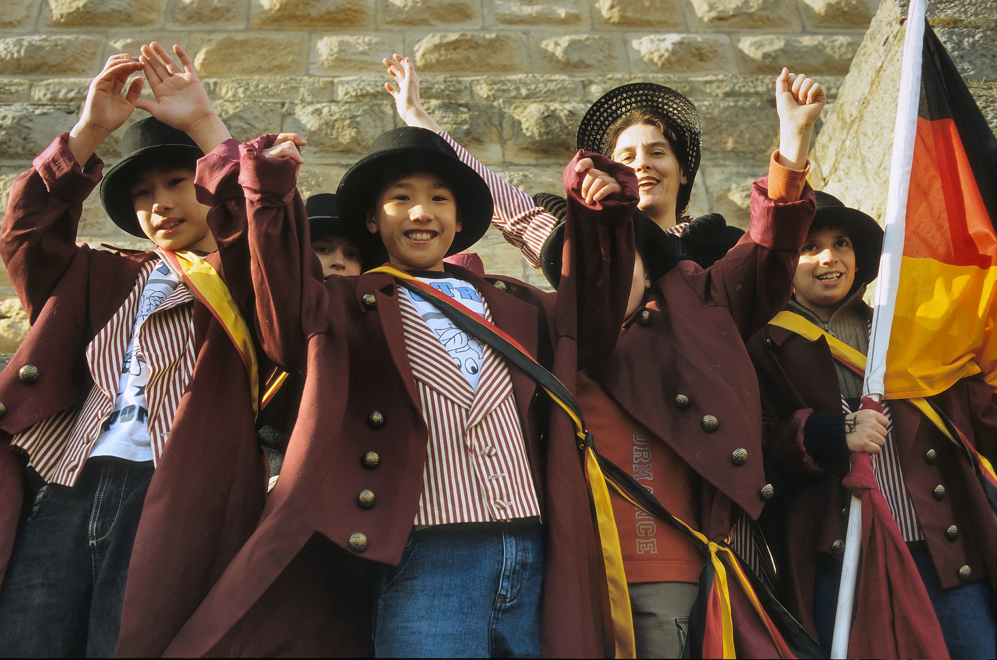 Jugendliche in historischen Kostümen winken fröhlich vor Hambacher Schloss